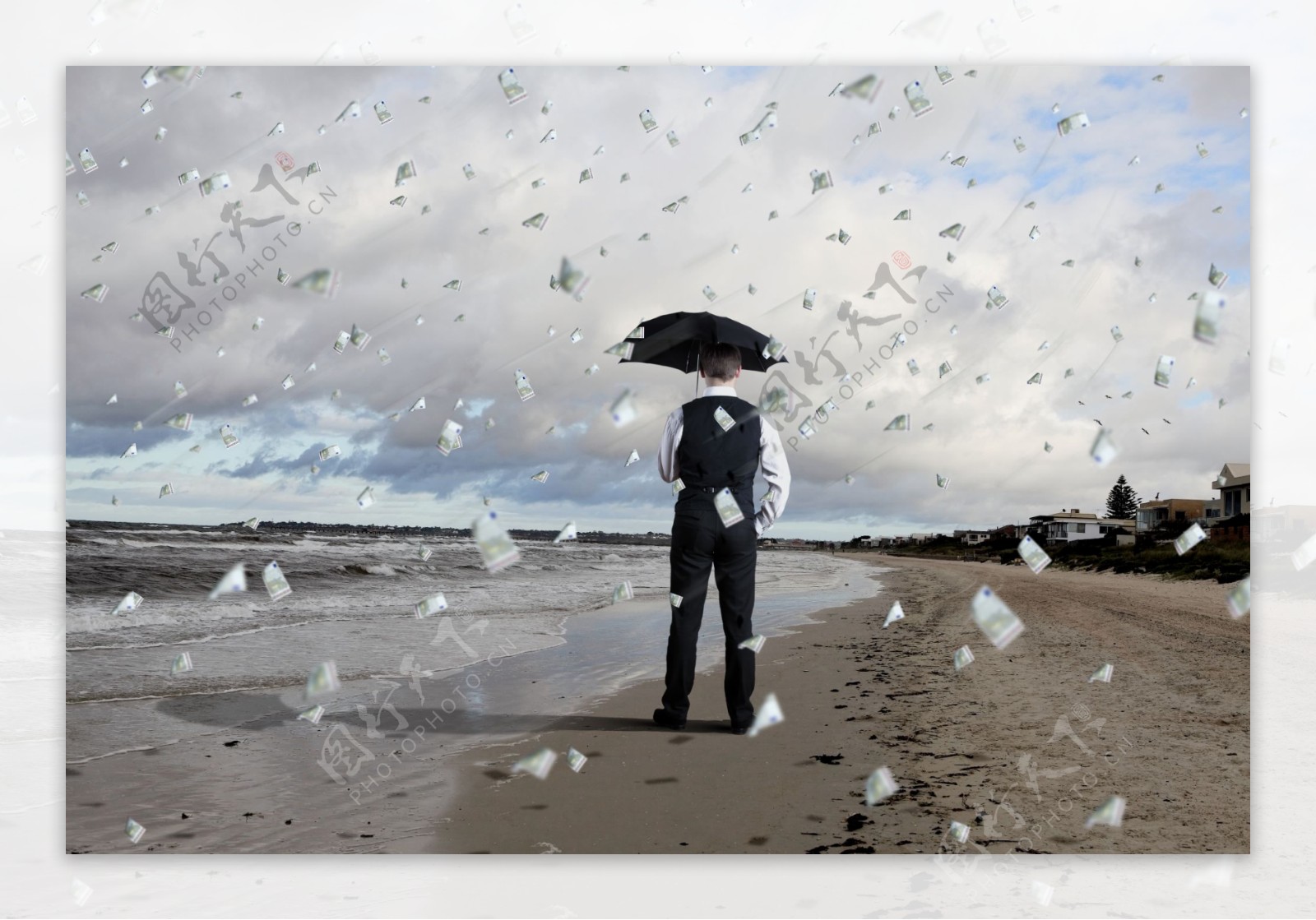 沙滩打着雨伞遮挡金钱雨的商务人物图片