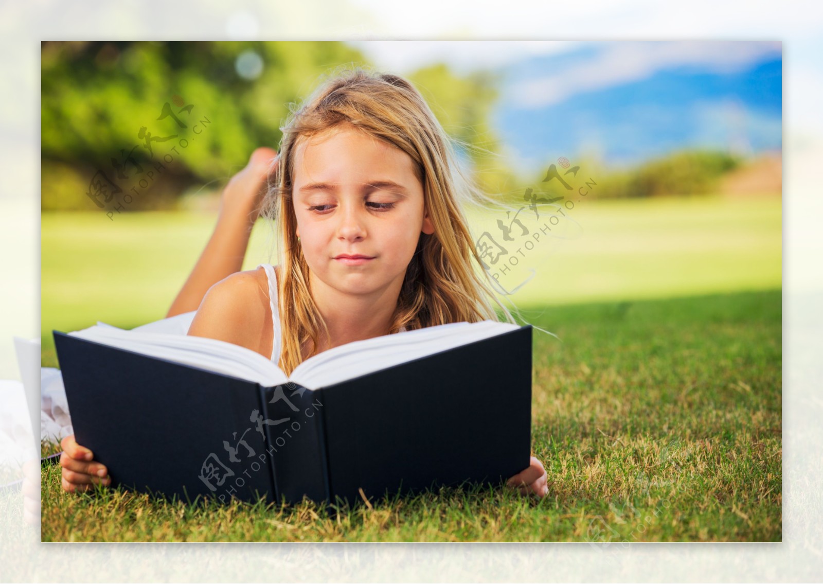 趴在草地上看书的外国小女孩图片
