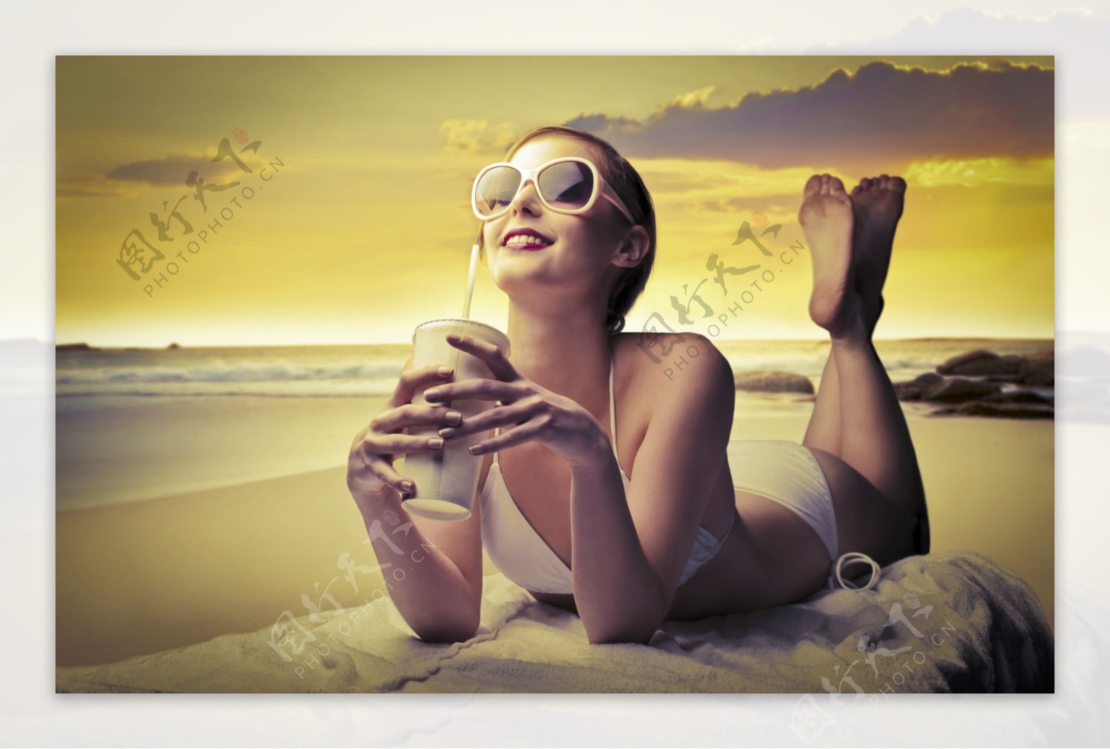 海边趴着喝饮料的美女图片