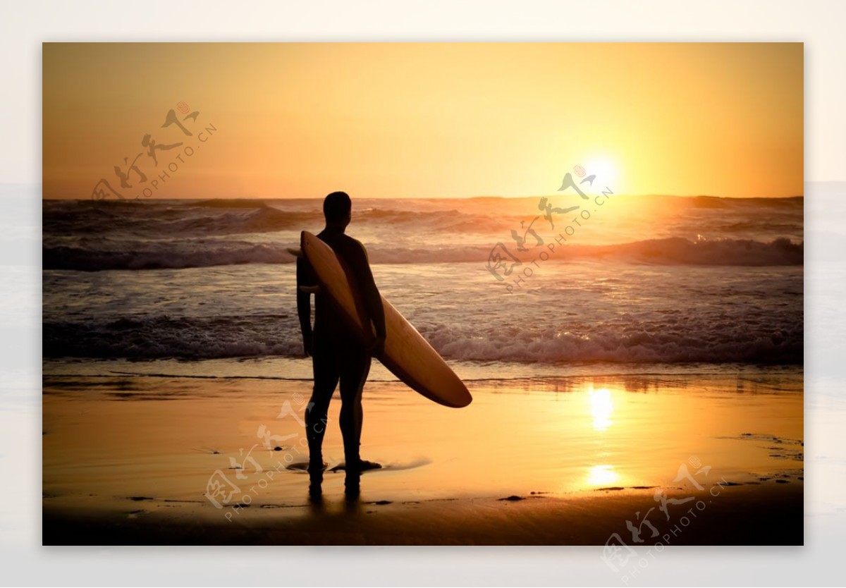 夕阳下拿着冲浪板的男人图片