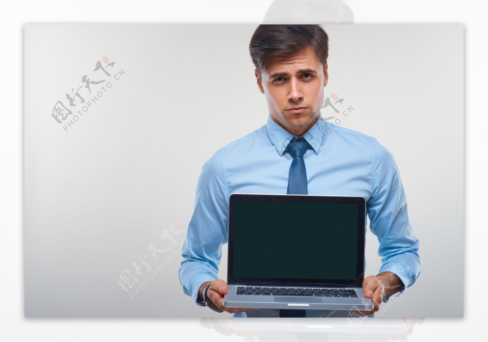 皱着额头拿着电脑的男士图片