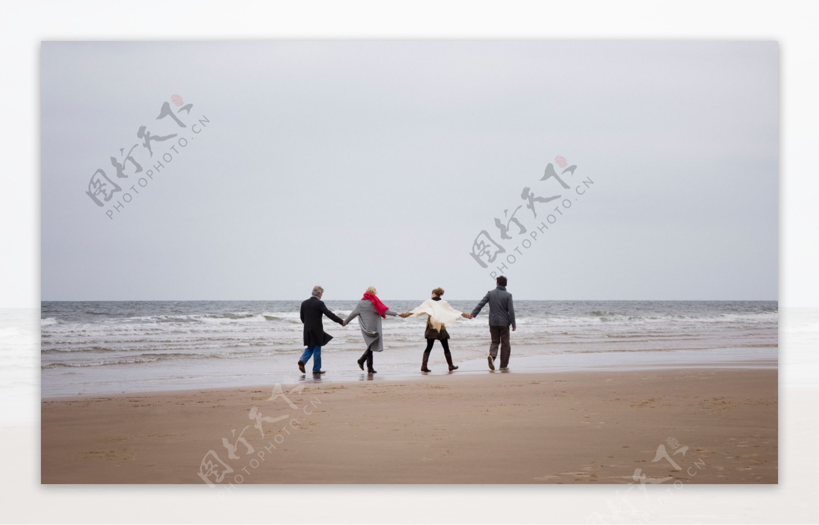 手牵手走在海边的一家人图片