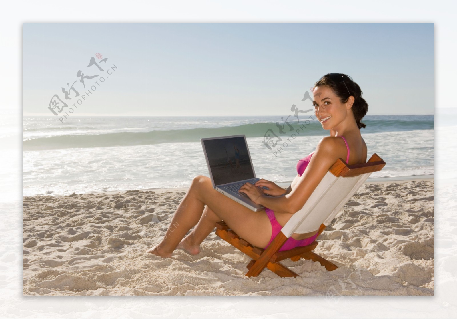 沙滩上玩笔记本电脑的美女图片
