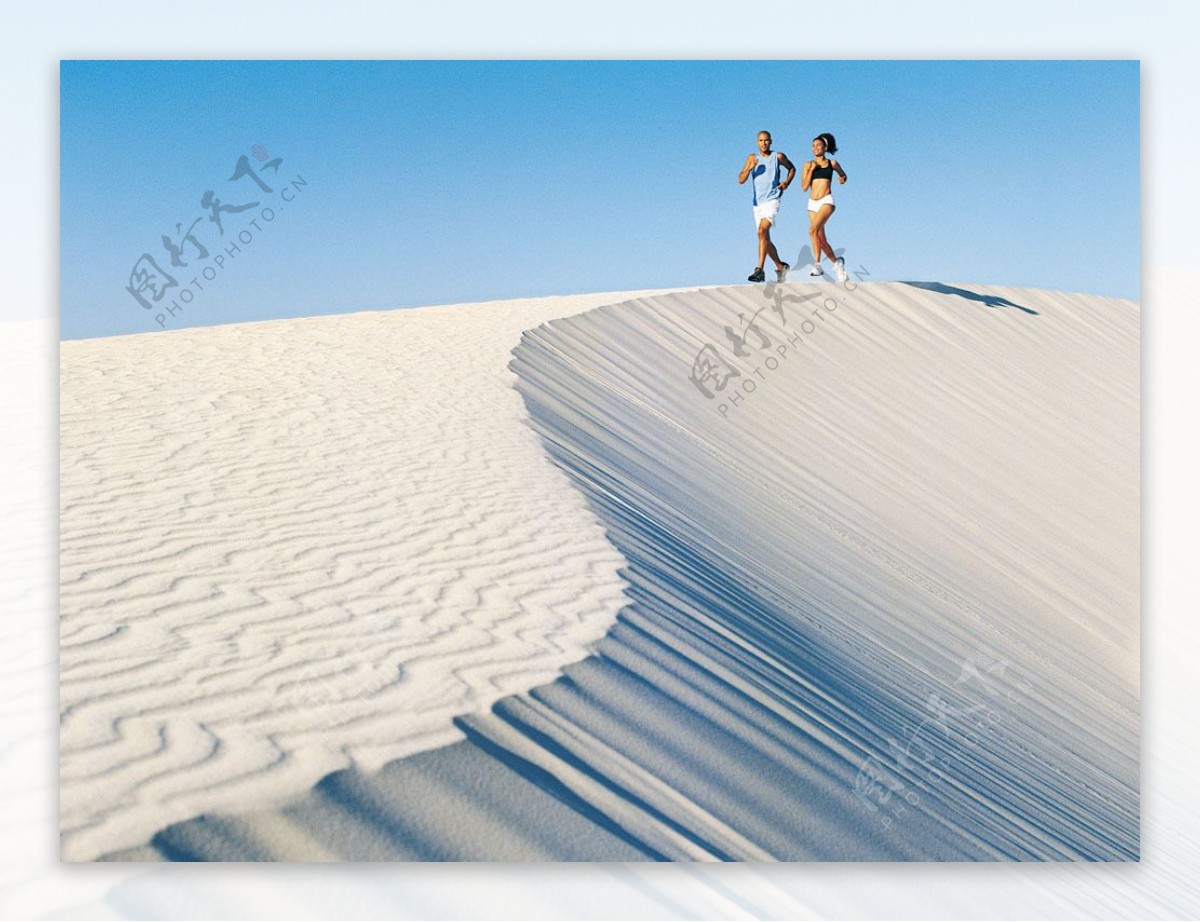 沙漠中迎着阳光奔跑的情侣图片