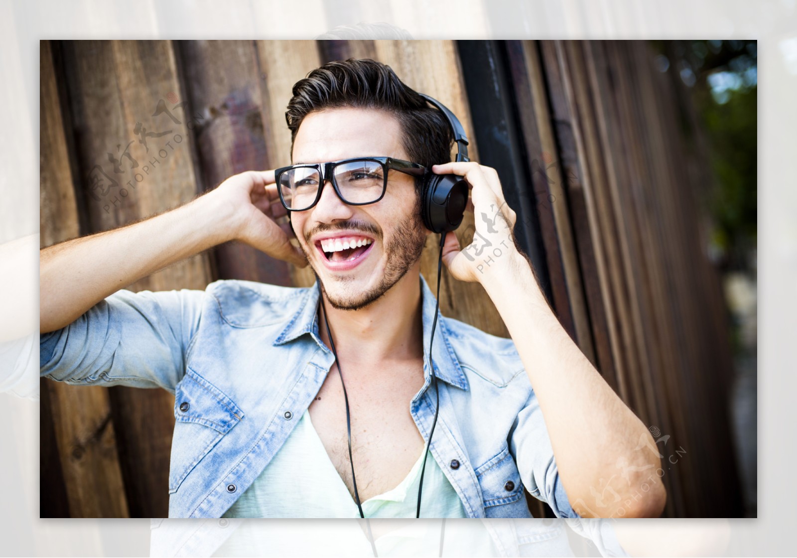 快乐的年轻男士在麦田里戴着耳机听音乐-蓝牛仔影像-中国原创广告影像素材
